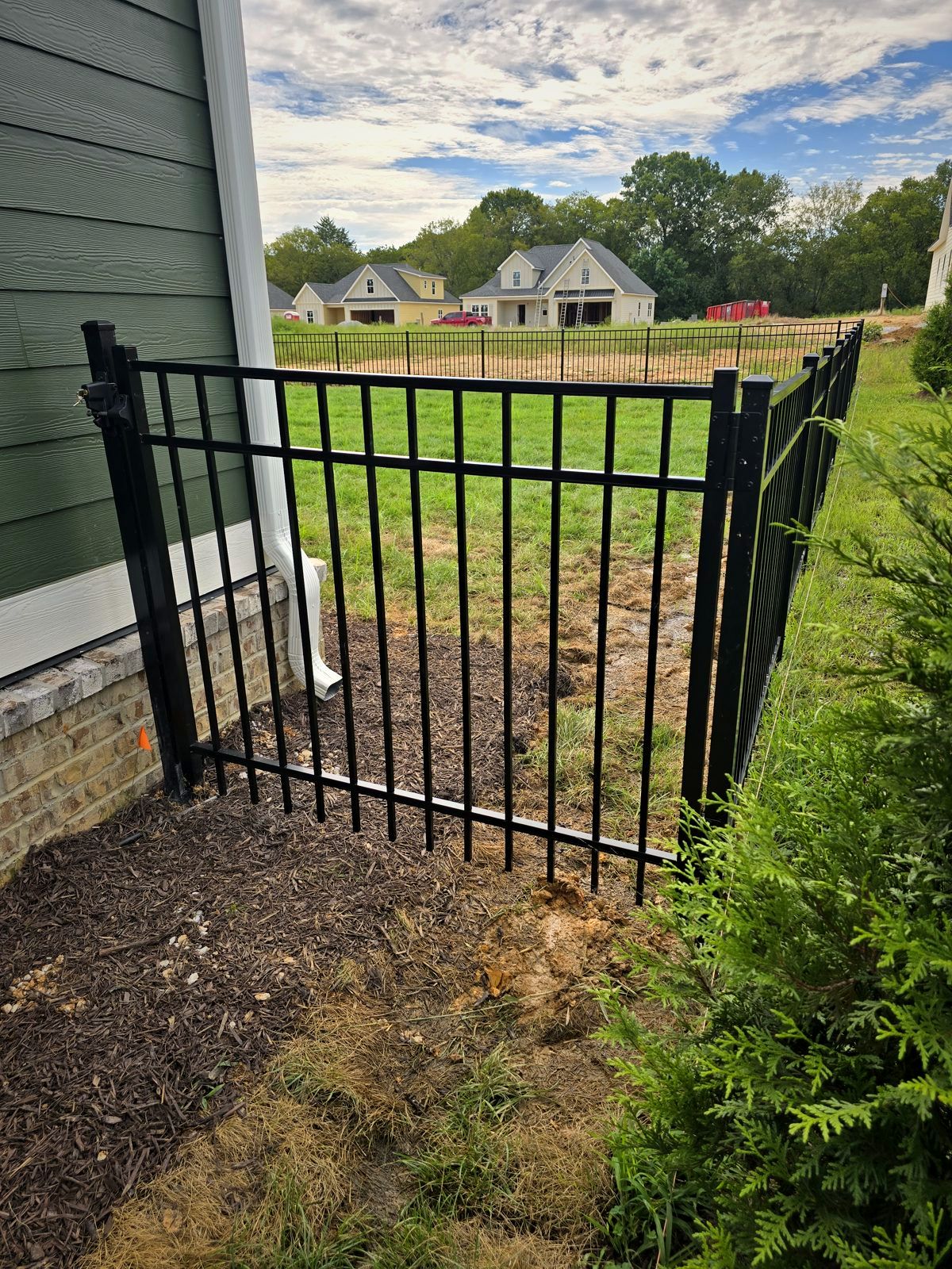 Black aluminum walk gate beside a new home