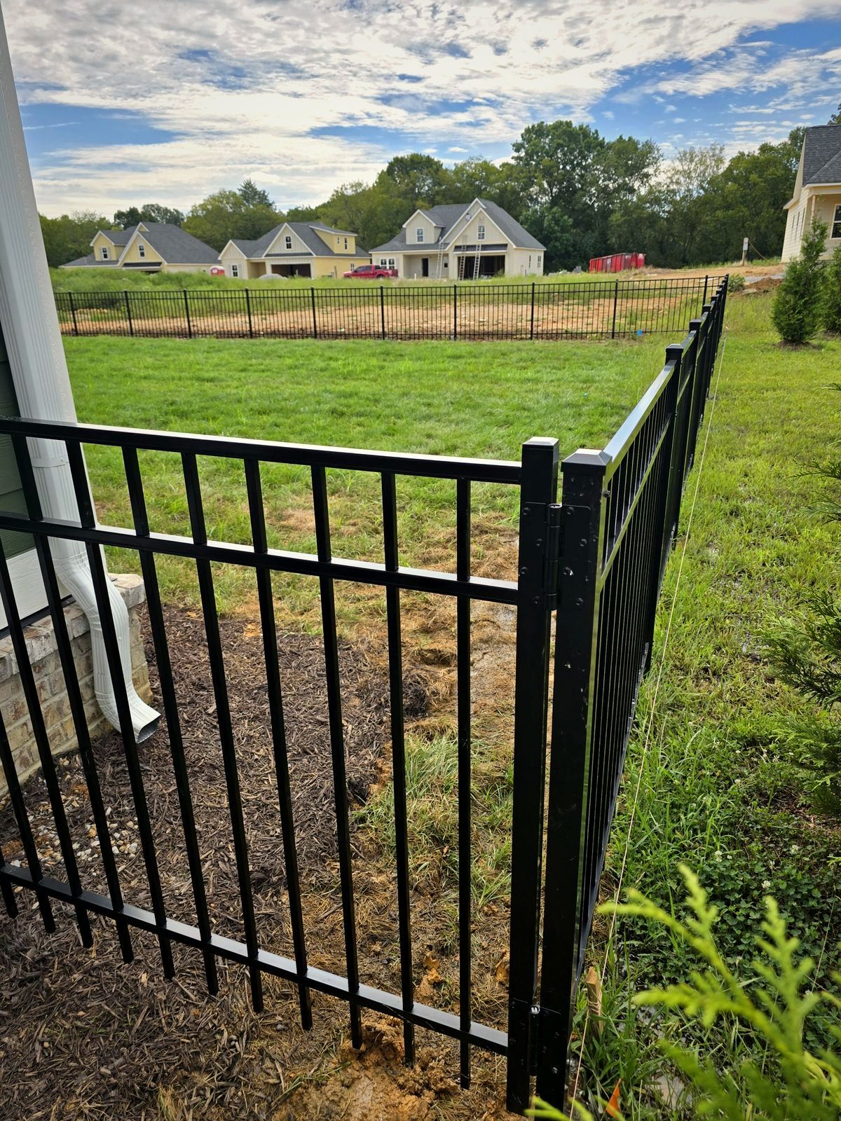 Black aluminum fence corner at a new home overlooking a subdivision