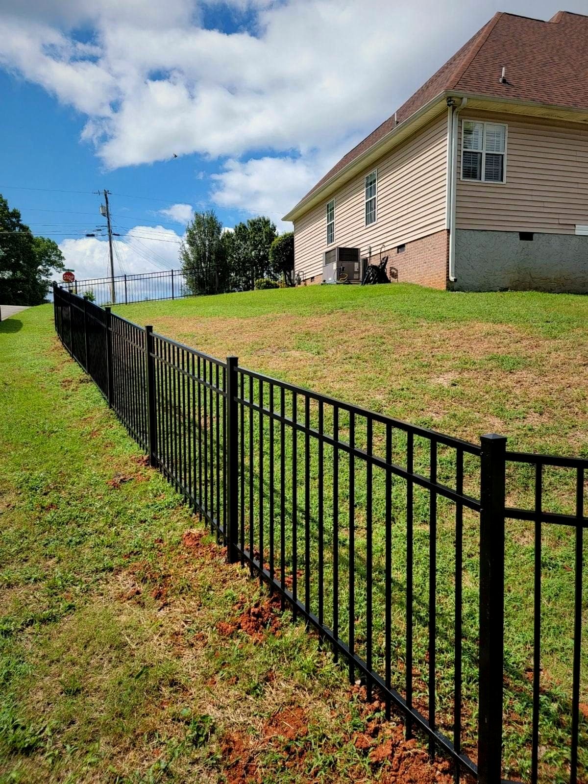 Black aluminum fence running down a sloped yard