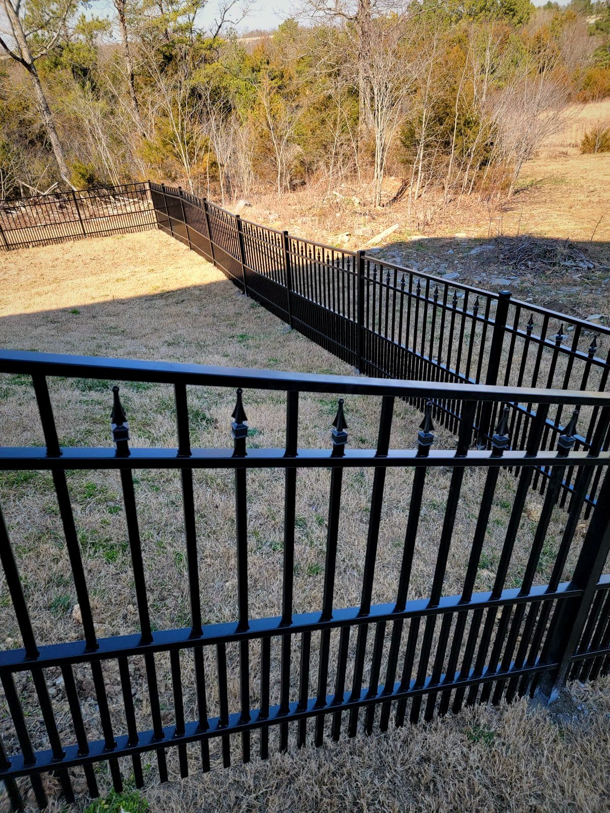 Black aluminum fence stepping down a sloped backyard