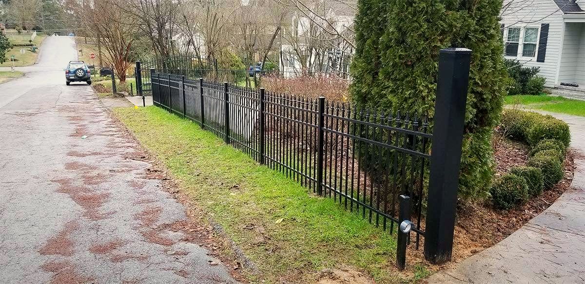 Black ornamental aluminum fence along a residential street beside landscaping