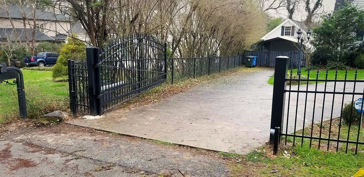 Black ornamental aluminum driveway gate with brick columns