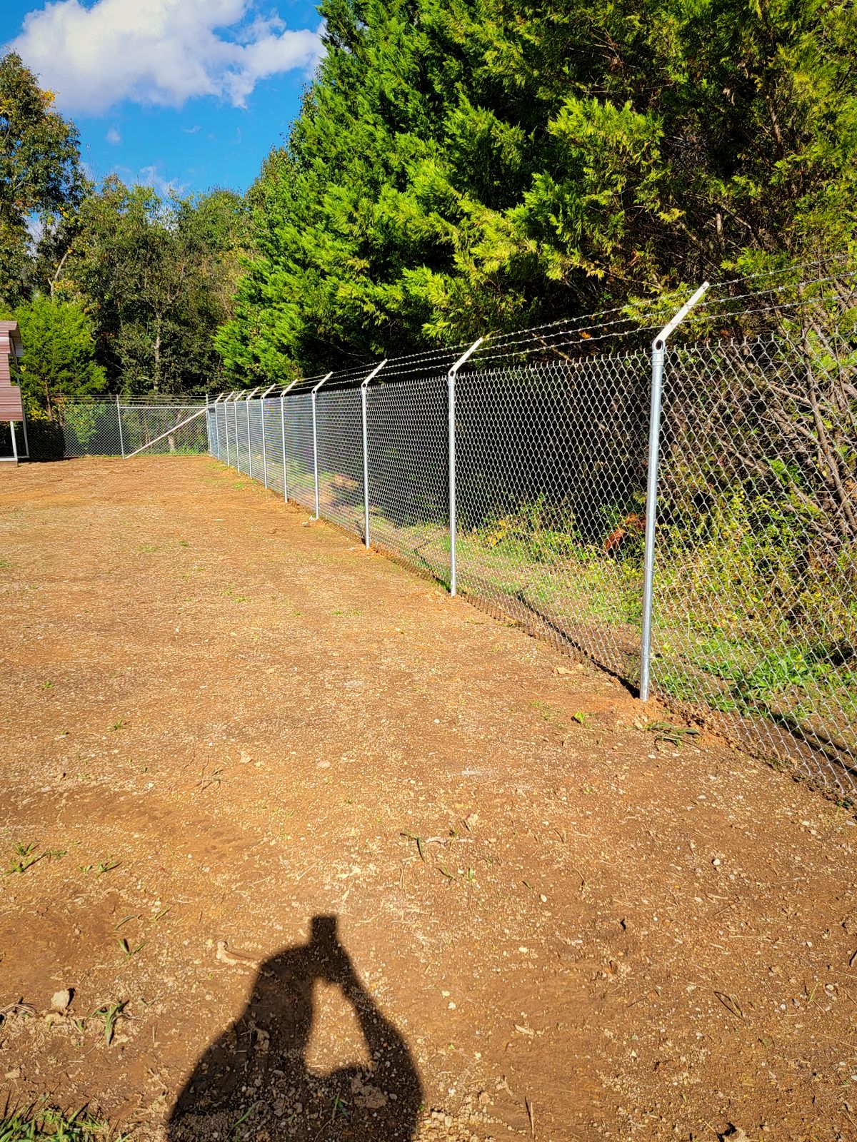 Galvanized chain link security fence along a graded lot