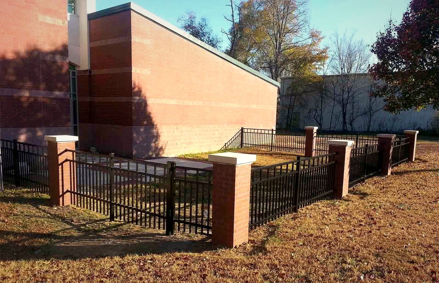Black aluminum fence between brick columns at a church