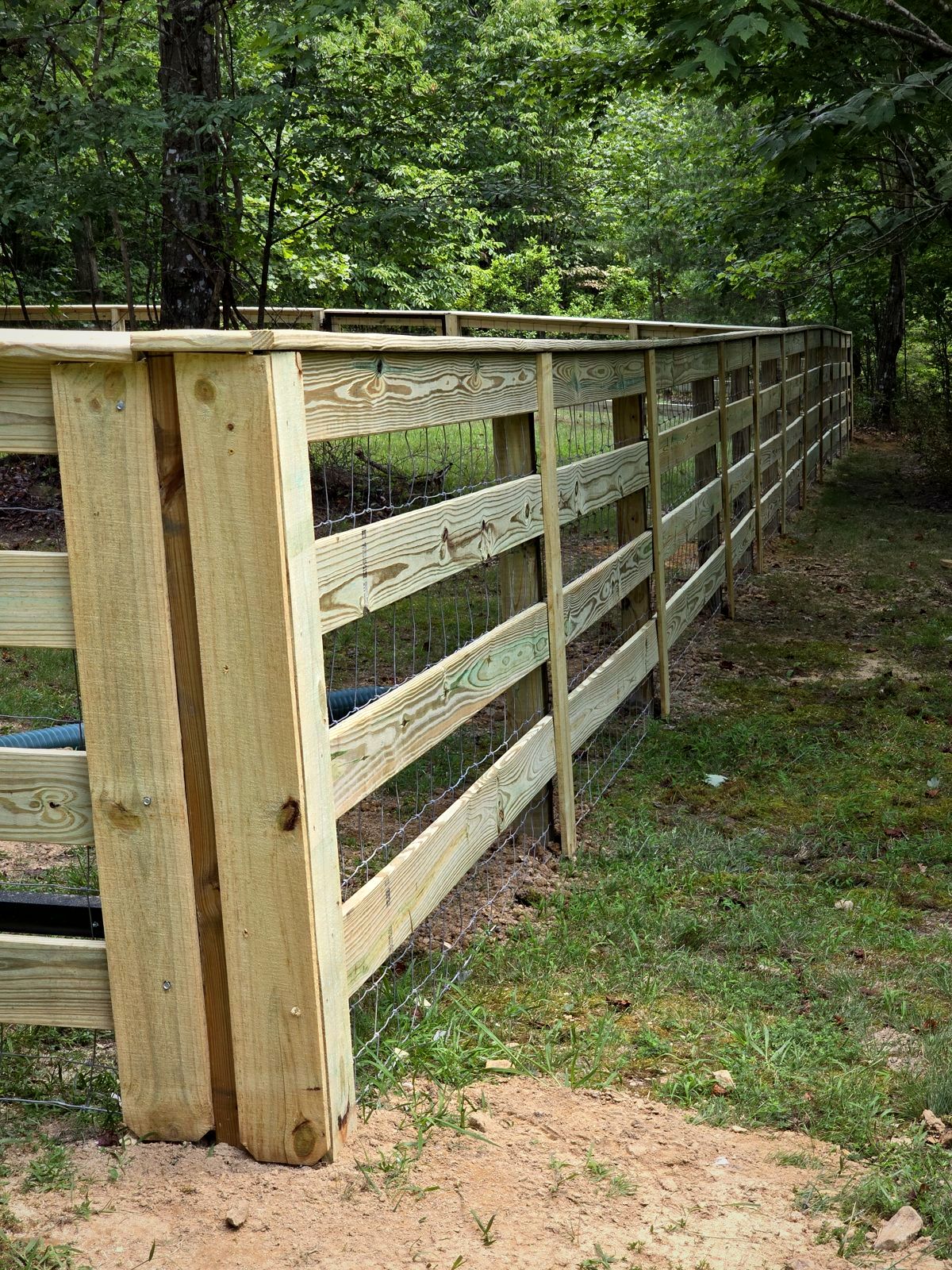 New three-rail wood fence with wire mesh