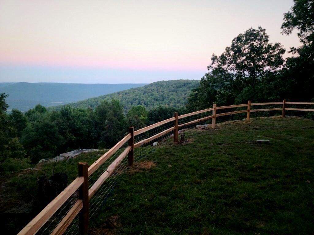 Split-rail fence following a hillside with a mountain view