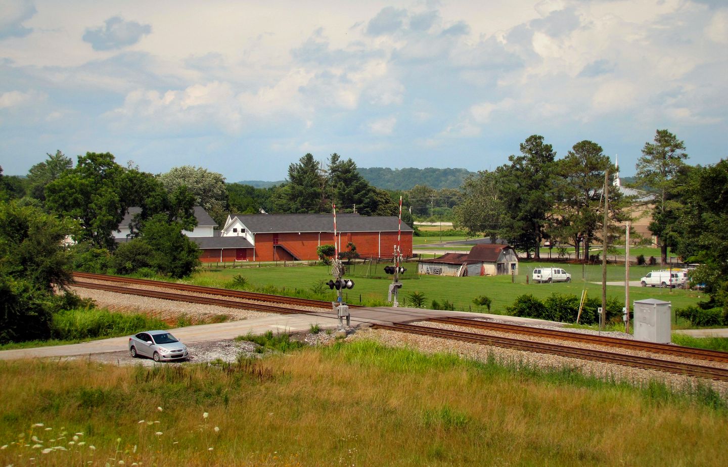 Farmland and red barns beside the railroad crossing at Reavley Road in Sale Creek, next door to Bakewell
