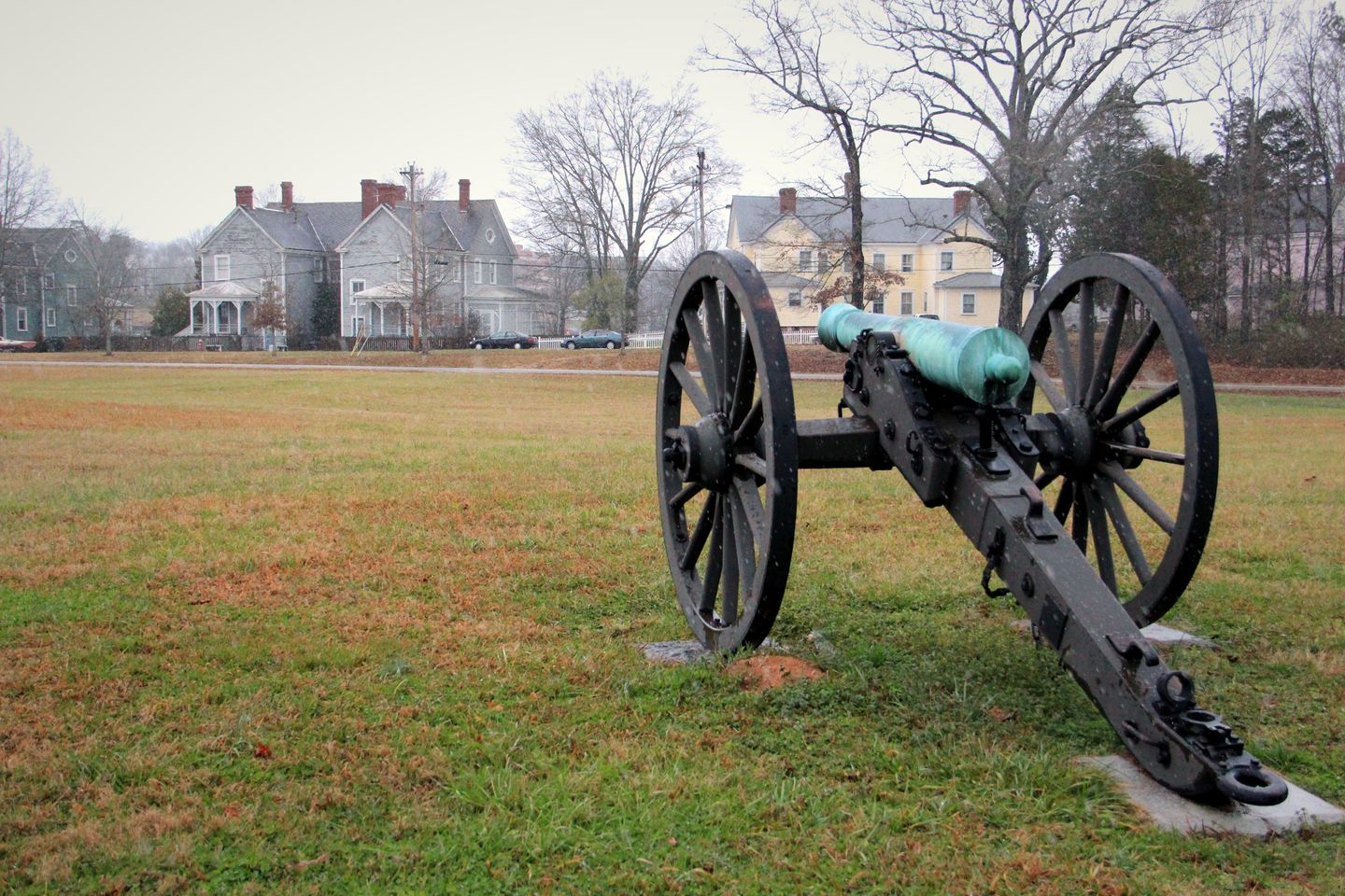 A Civil War cannon on the Chickamauga battlefield with the historic homes of Barnhardt Circle in Fort Oglethorpe behind it