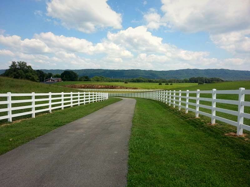 White four-rail vinyl fence along a drive with mountains behind