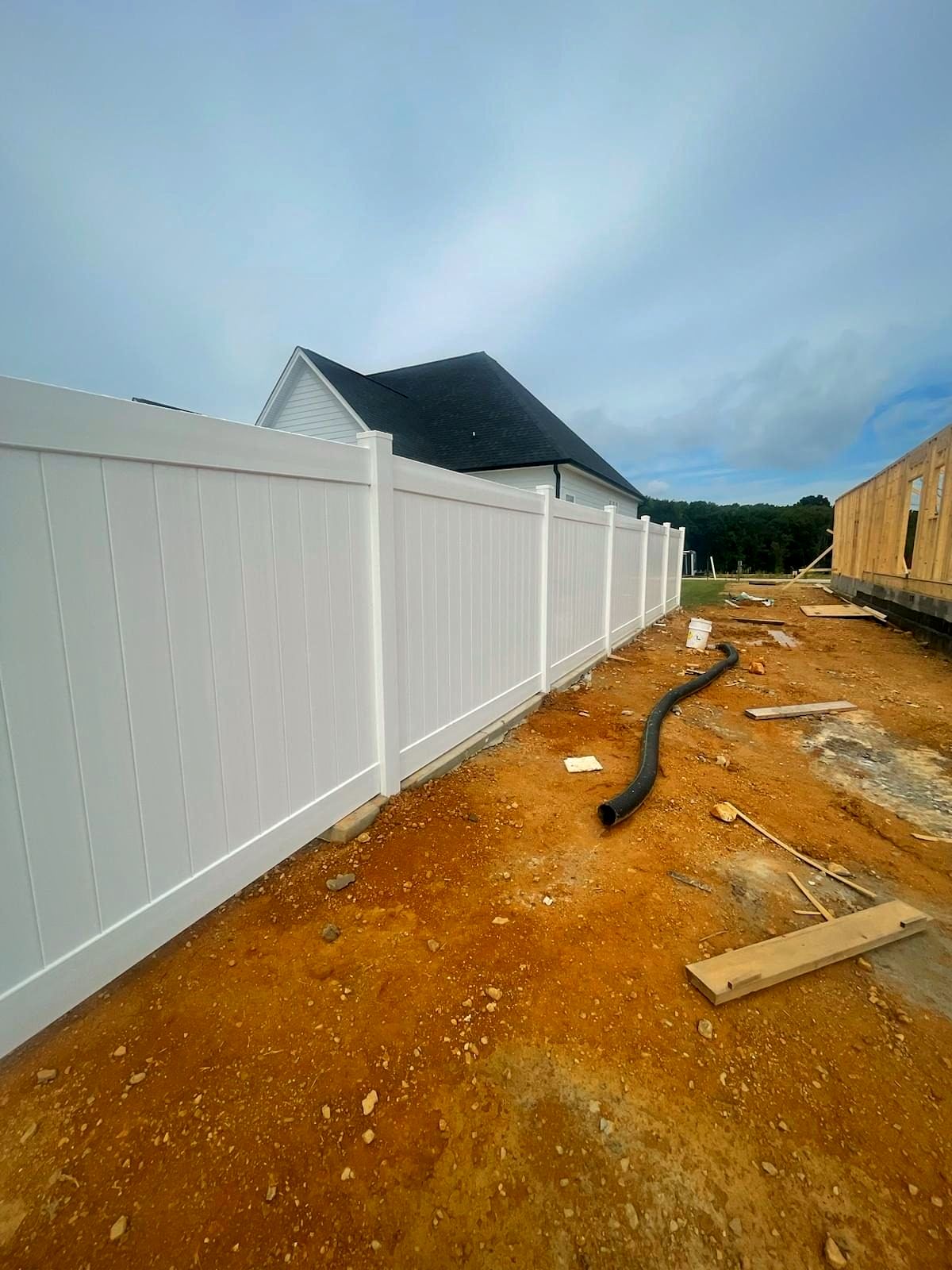 White vinyl privacy fence beside a home under construction