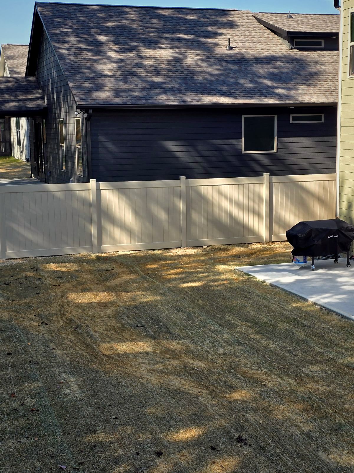 Grey vinyl privacy fence beside a dark house