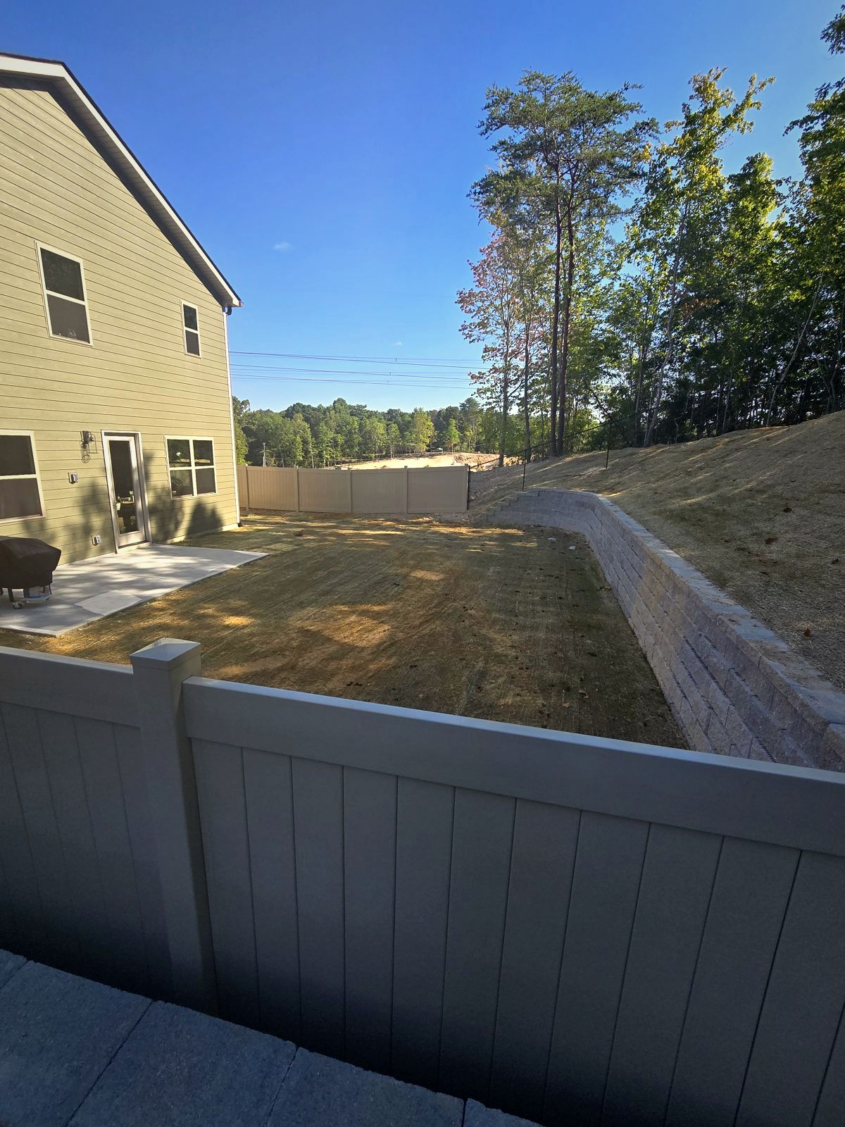 Gray vinyl privacy fence above a stone retaining wall