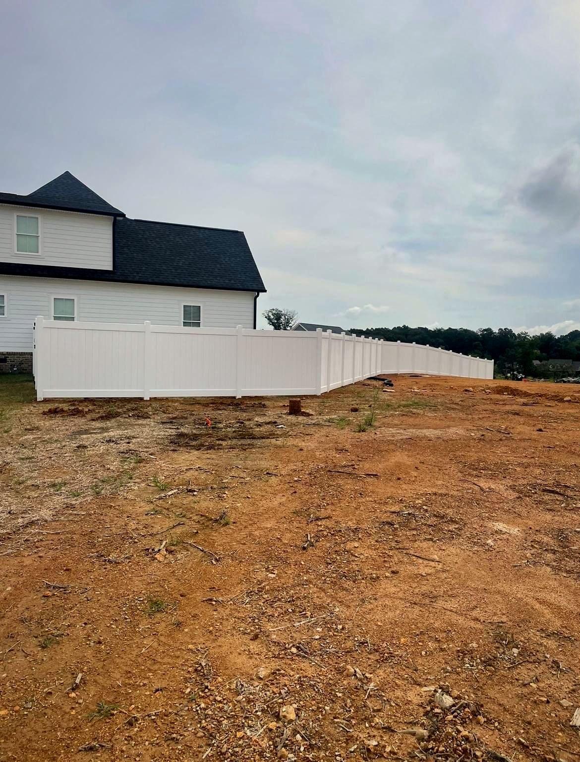 White vinyl privacy fence around a newly graded backyard
