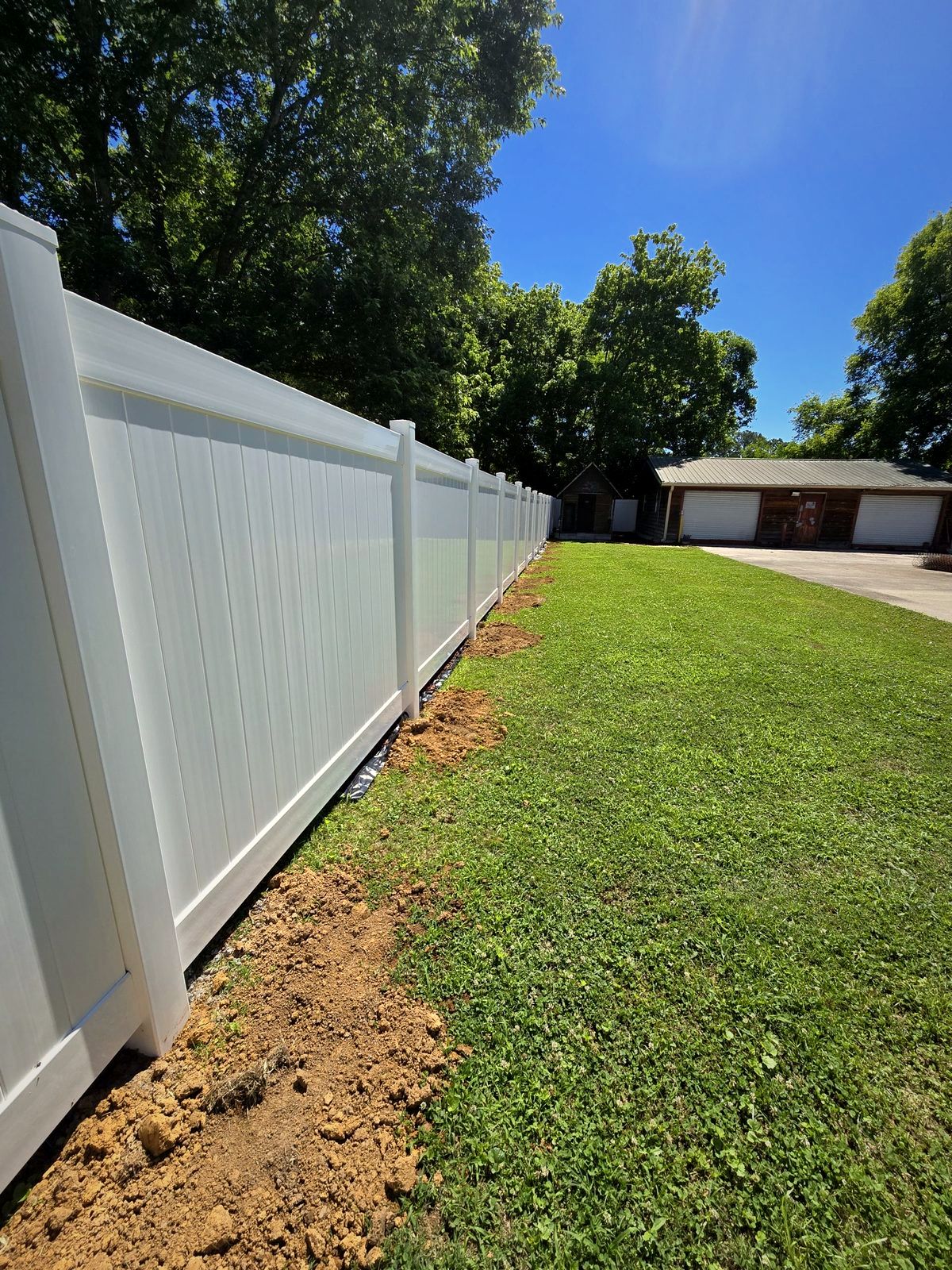 White vinyl privacy fence along a backyard lawn