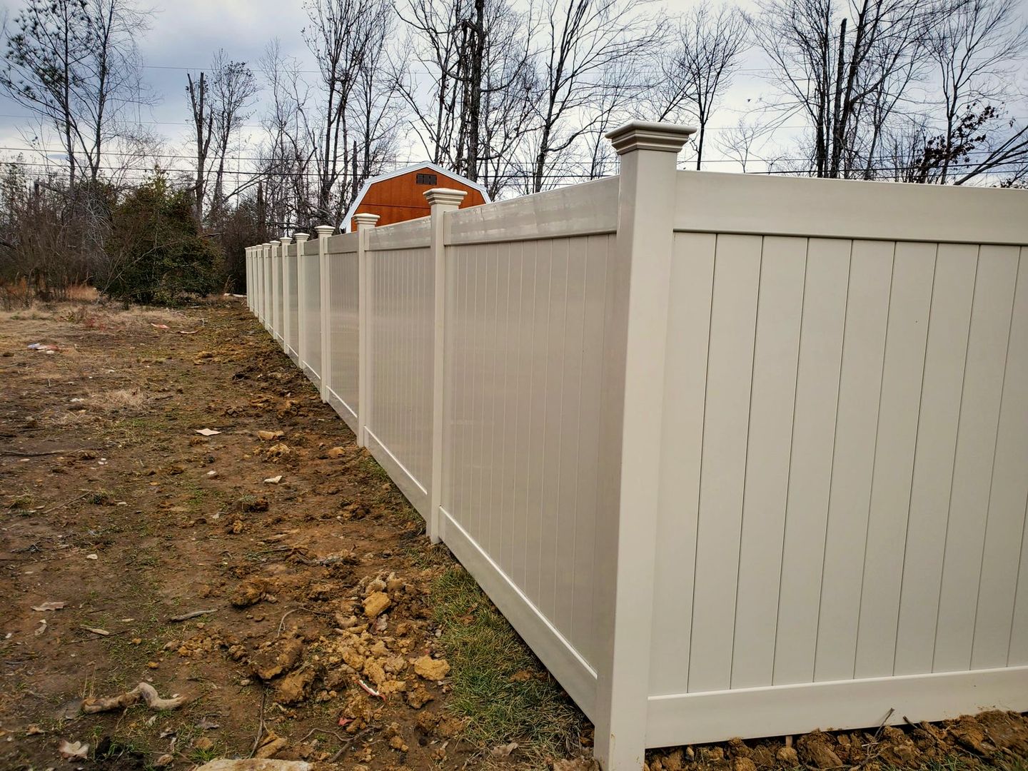 Tan vinyl privacy fence running along a property line