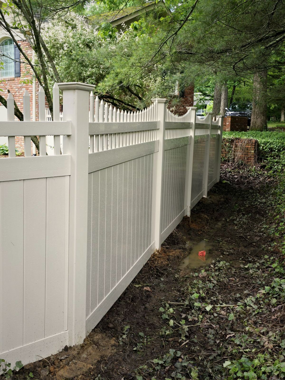 Tan vinyl privacy fence with a picket top