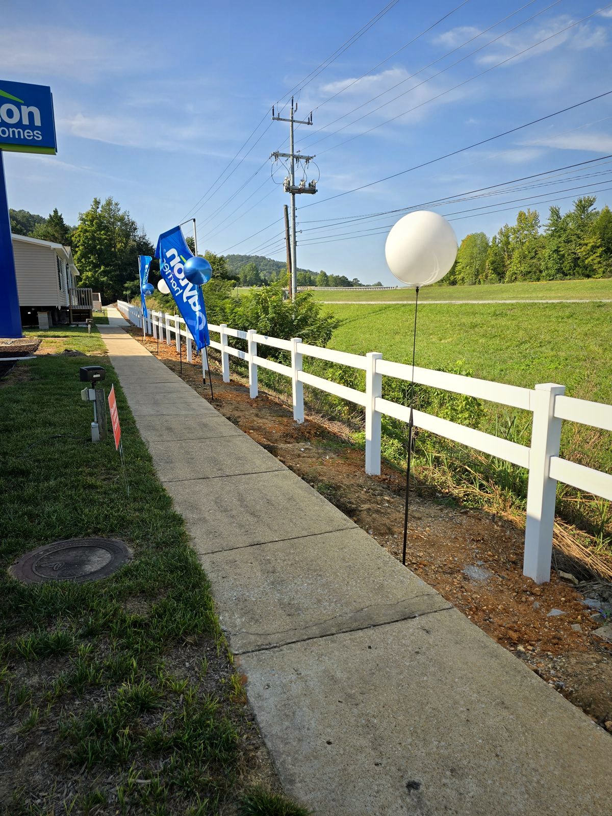 White vinyl two-rail fence along a sidewalk