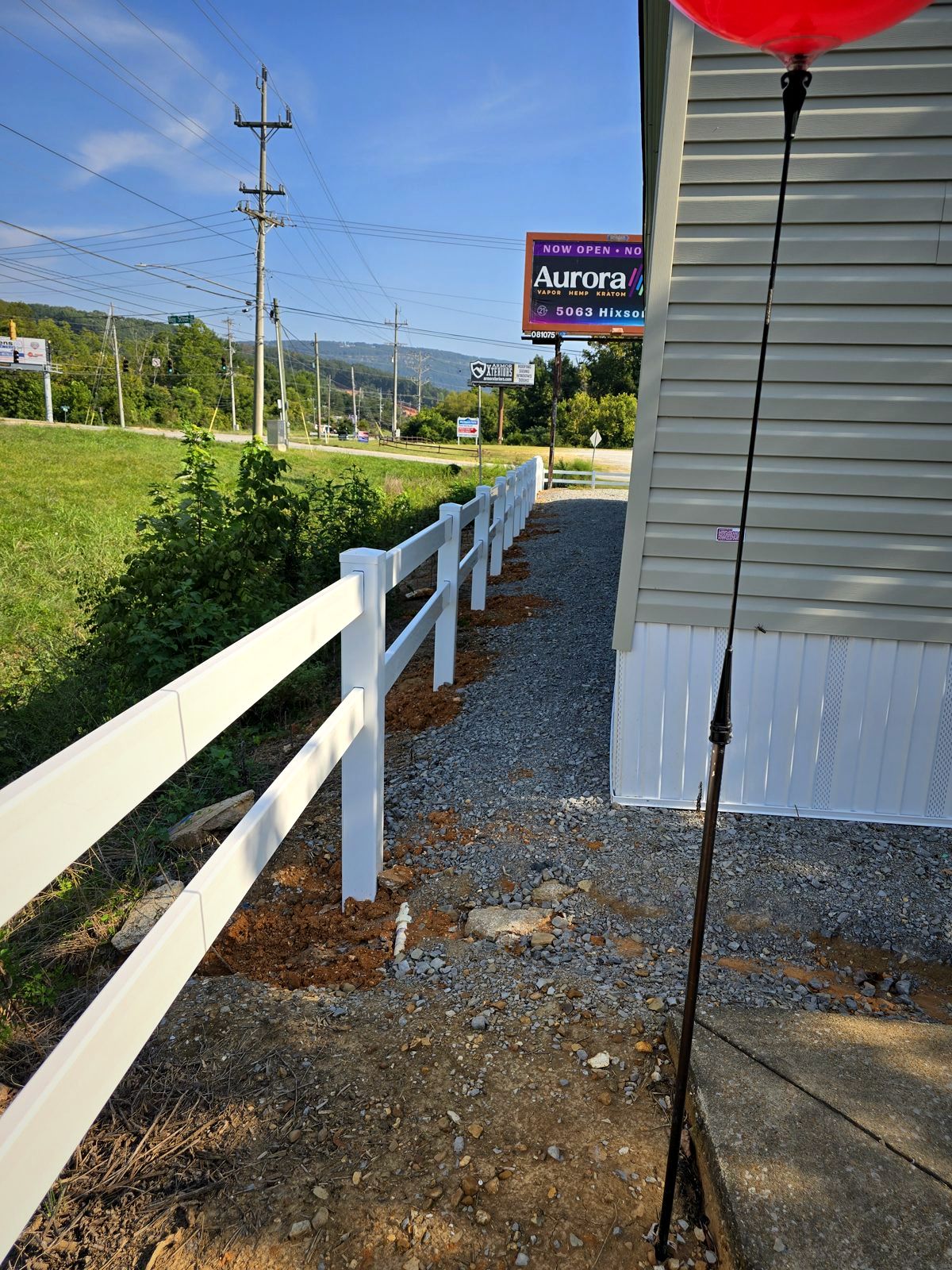 White vinyl two-rail fence beside a commercial building