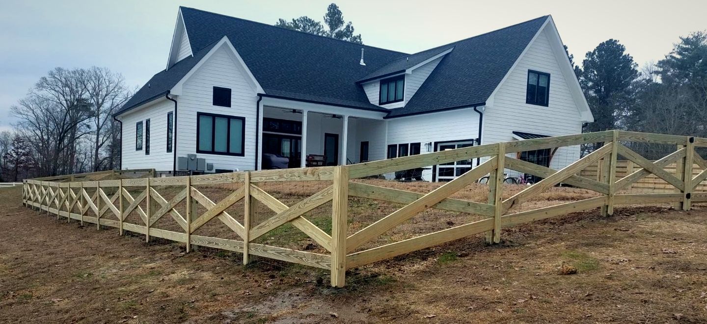 Wood cross-rail fence in front of a white farmhouse