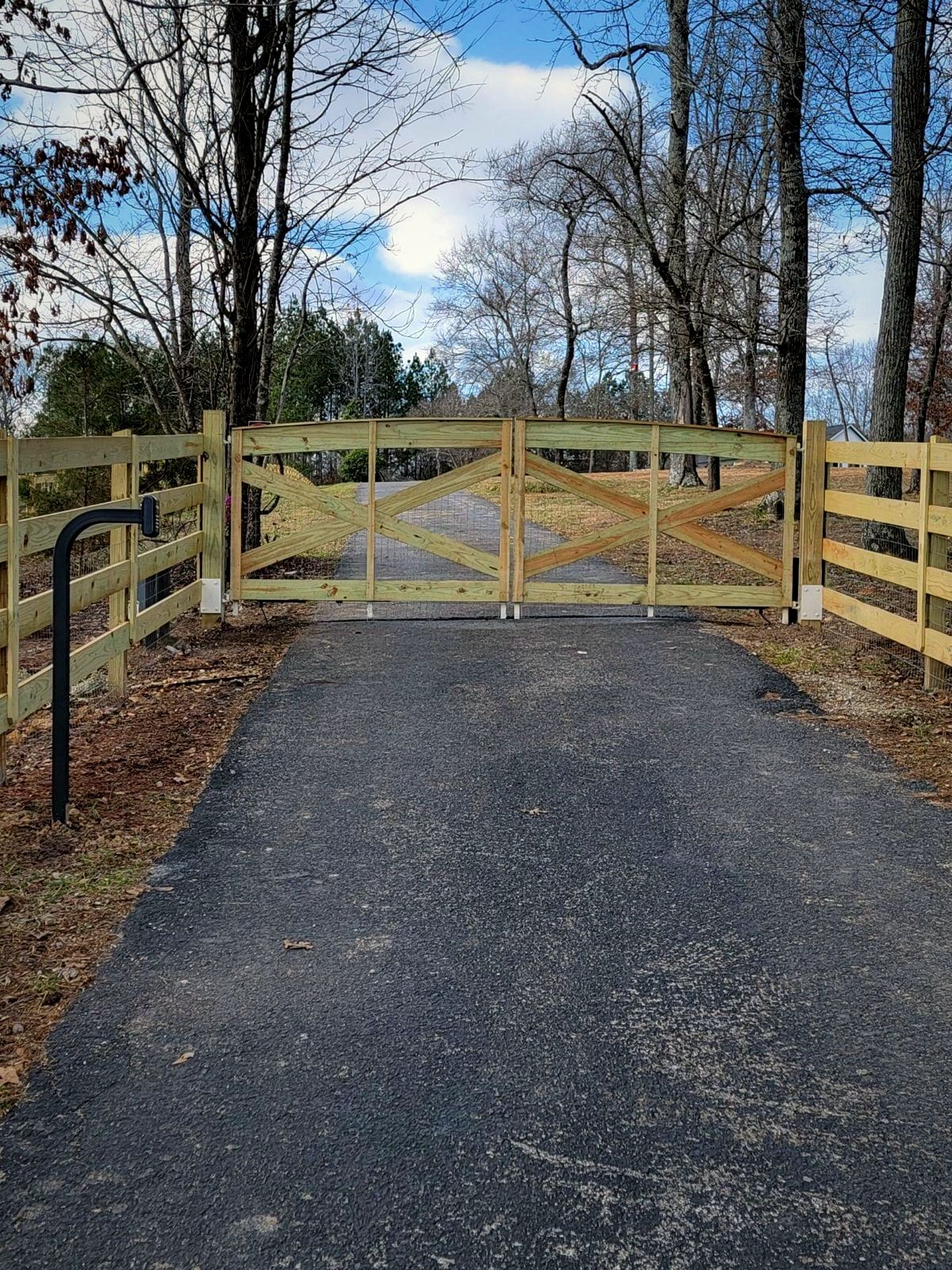 Wood farm gate across a paved drive