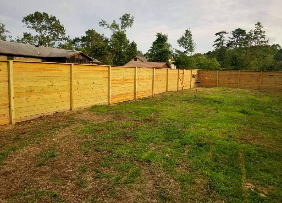Horizontal-board wood privacy fence around a backyard lawn