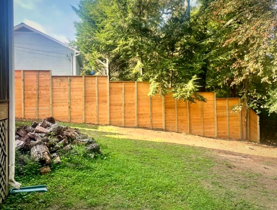 Horizontal-board cedar-tone privacy fence across a backyard