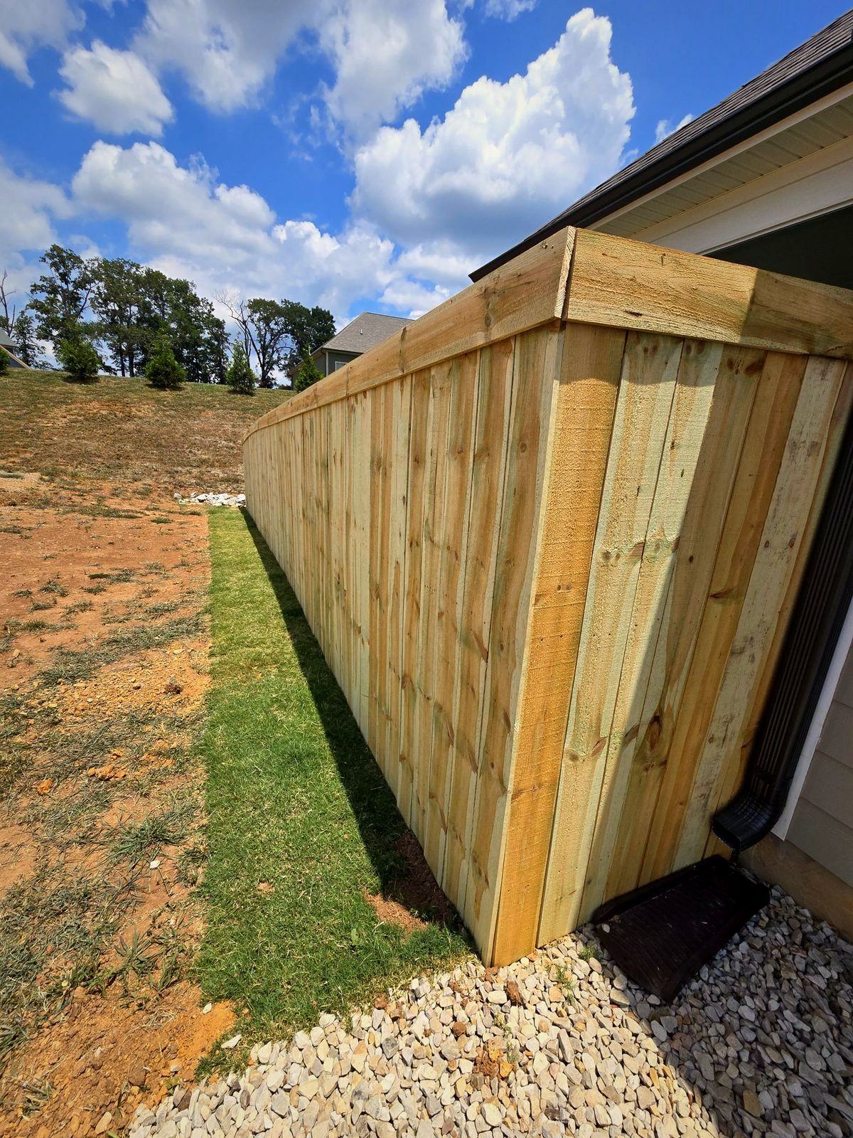 Capped wood privacy fence along the side of a home
