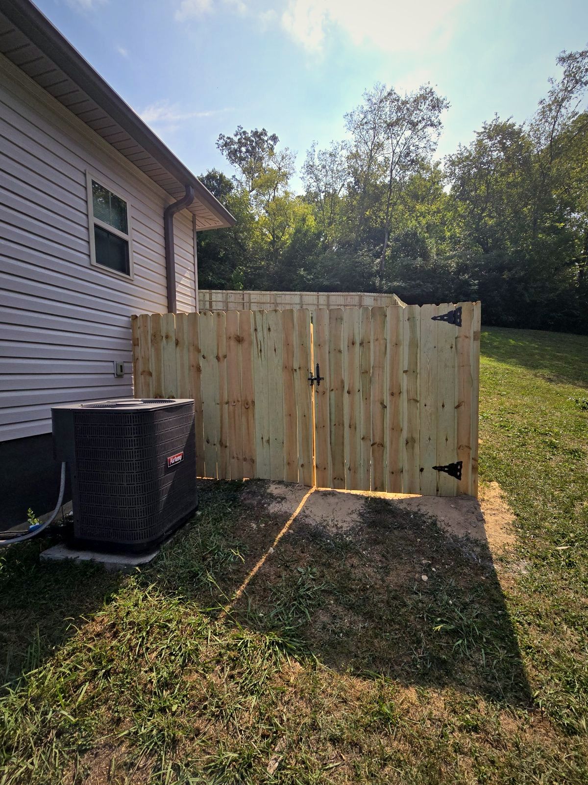 Wood privacy fence with a double gate beside a home