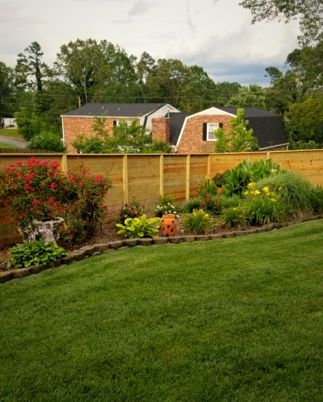 Wood privacy fence beside flower beds with a valley view