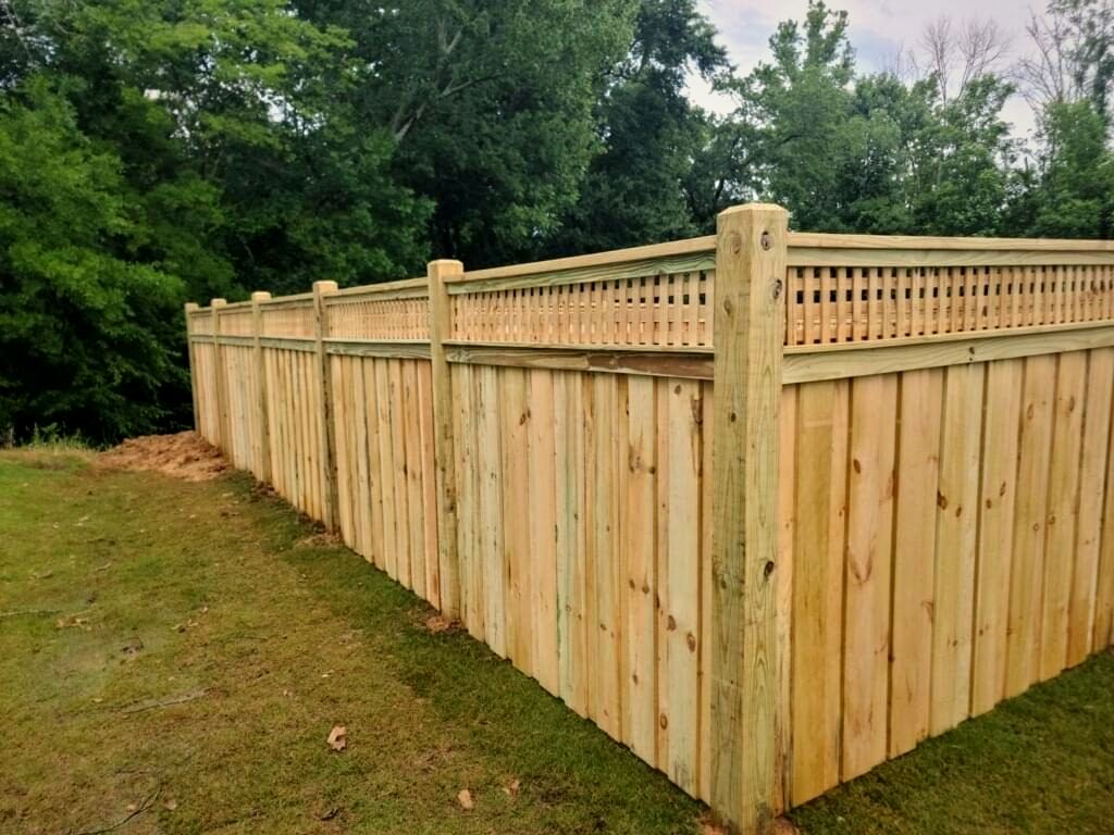 Wood privacy fence with a lattice top around a green lawn