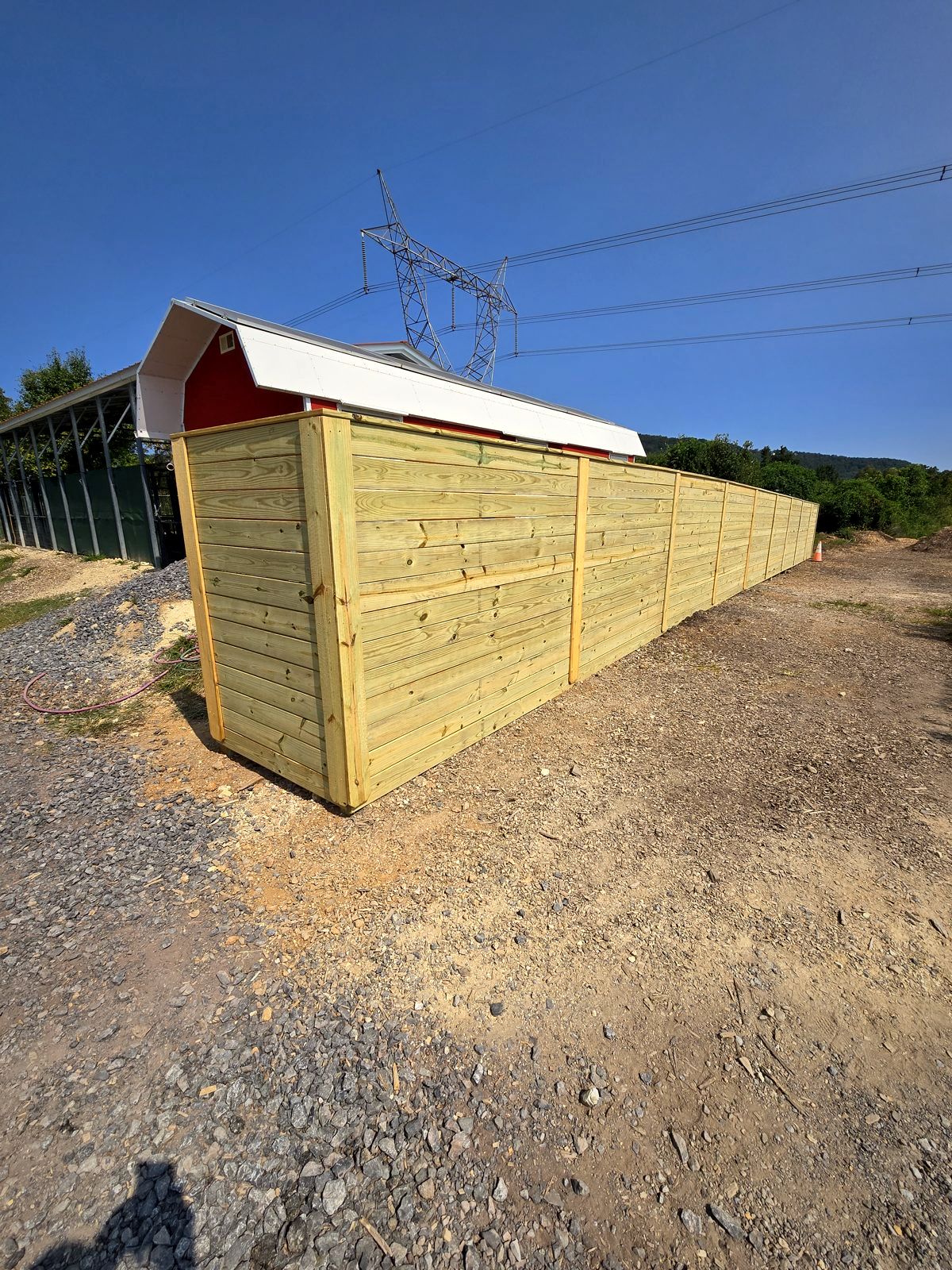 New wood privacy fence running past a red barn