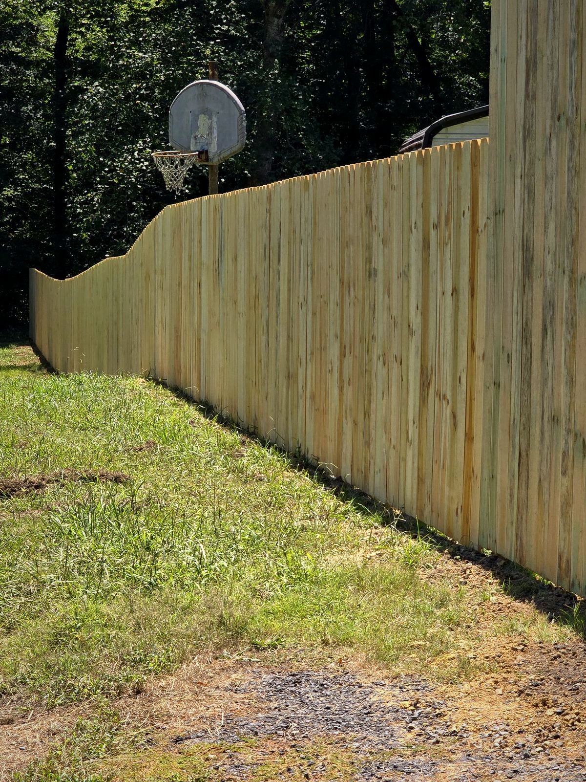 Tall wood privacy fence following a slope